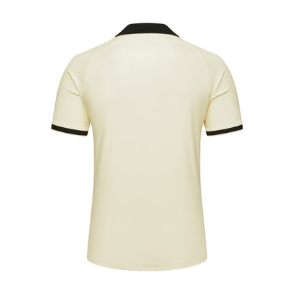 A short-sleeve polo shirt shown from the back, featuring a warm cream body with black trim on the collar and sleeve cuffs, set against a plain white background.